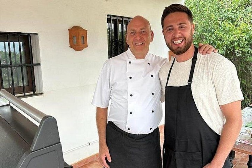 Two individuals in a kitchen setting, one in a chef's uniform and the other in casual attire. 2