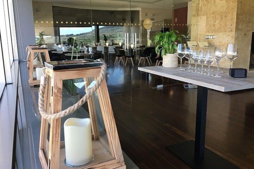 A modern dining area with wooden tables, a white candle, and wine glasses. 1