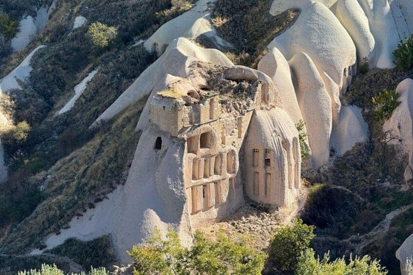 Una formazione rocciosa con una struttura scolpita che ricorda una casa. 3