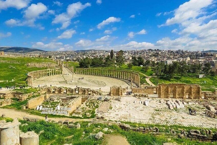 Un anfiteatro antiguo con ruinas y un paisaje urbano al fondo. 5