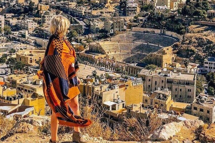 Una persona de pie en una colina con vistas a una ciudad y un gran anfiteatro. 1