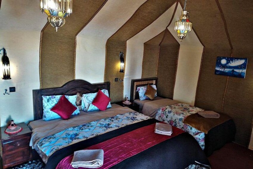 Een slaapkamer met twee bedden, decoratieve kussens, een nachtkastje en wandlampen. 2
