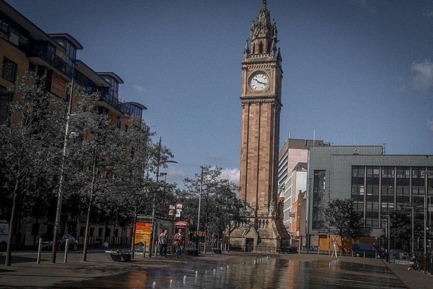 A clock tower, a modern building, and a wet plaza. 2