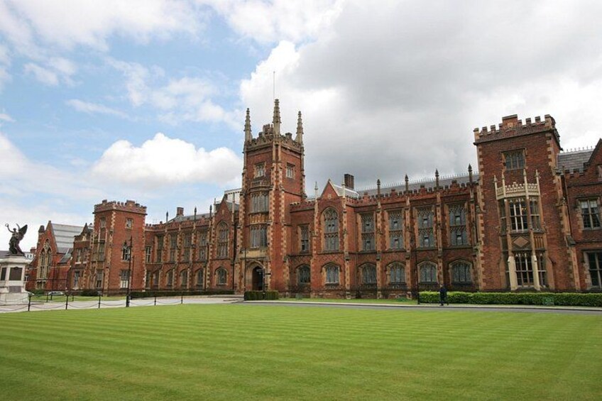A large, historic brick building with multiple towers and arched windows, surrounded by a well-maintained lawn. 5
