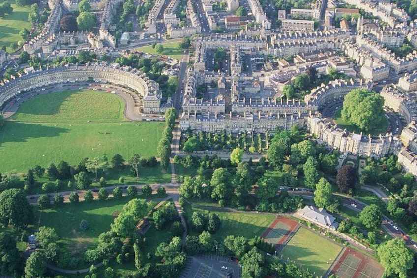 An aerial view of a historic town with a large circular park, dense tree coverage, and a prominent castle-like structure. 2