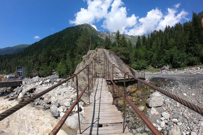 A wooden bridge over a rocky terrain with a mountainous background. 3