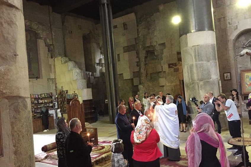 A group of people in a historical building with stone walls and columns. 5