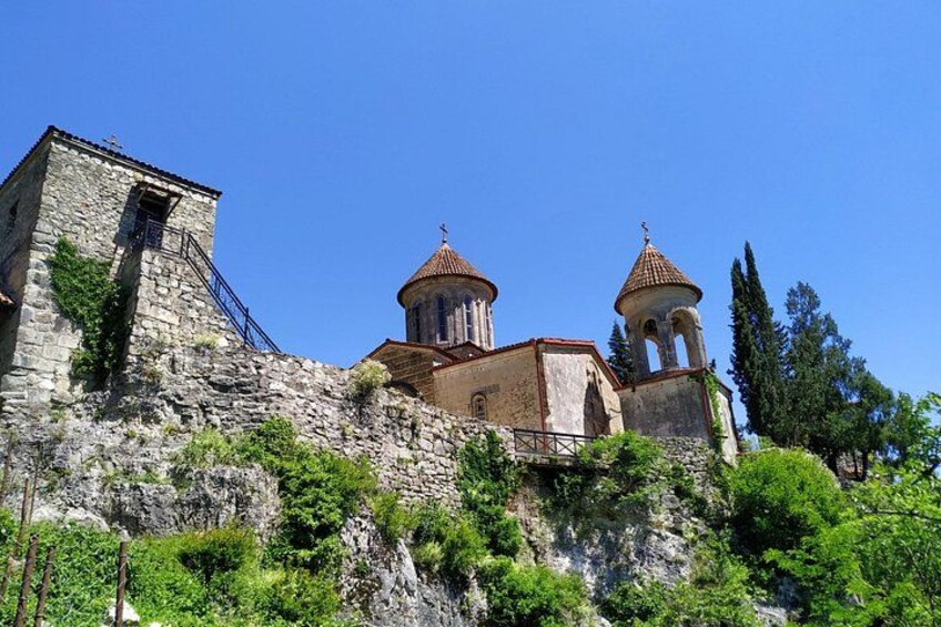 A historic stone church with two bell towers and a fortified wall. 3