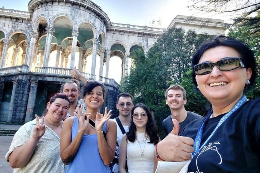 Eine Gruppe von Personen macht ein Selfie vor einem historischen Gebäude mit Bögen. 2