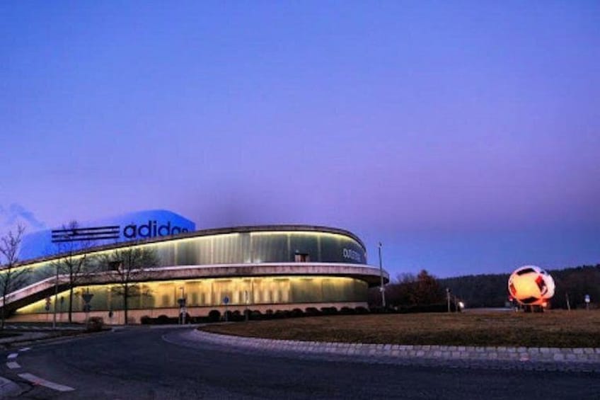 A modern building with a curved facade and the Adidas logo. 5