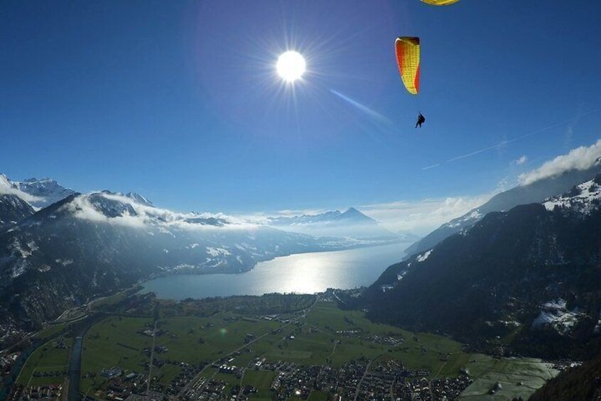 A person paragliding over a mountainous landscape with a lake below. 5