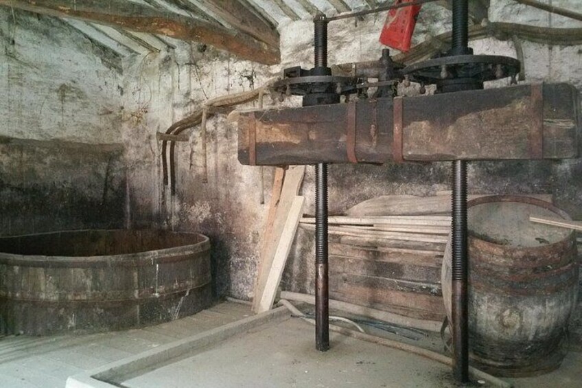 An old, industrial setting with rusted metal machinery, wooden barrels, and a large wooden beam. 2