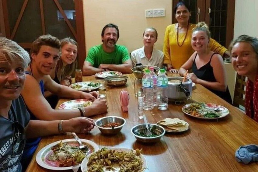 Un grupo de personas sentadas alrededor de una mesa de madera con diversos platos y bebidas. 3