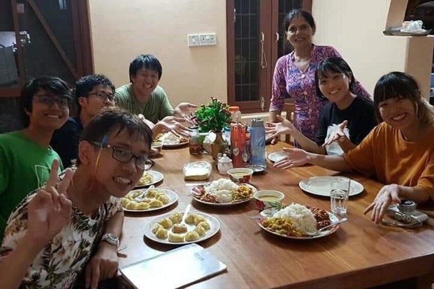 Un grupo de personas sentadas alrededor de una mesa de madera con diversos platos y bebidas. 2