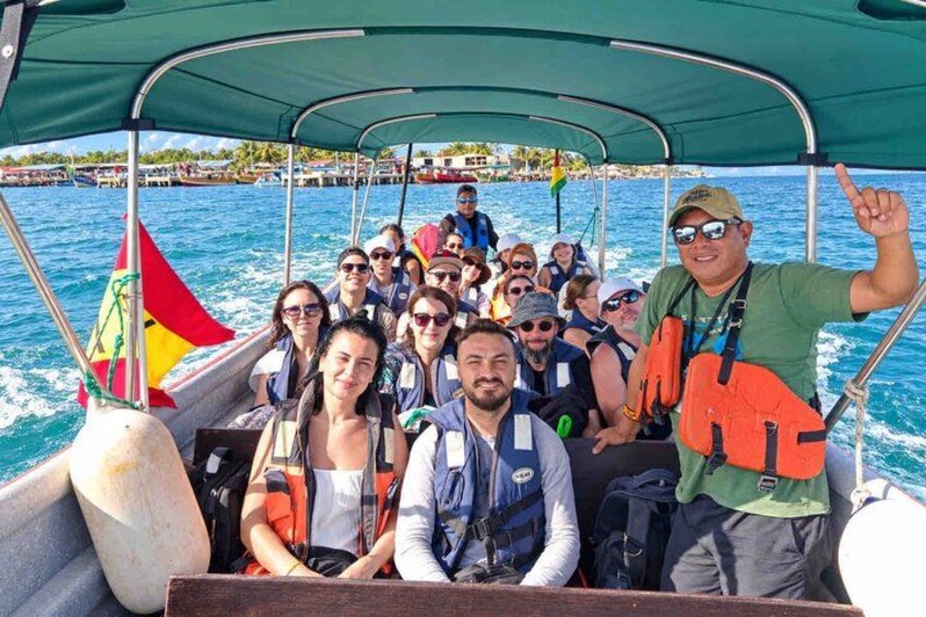 Un groupe de personnes à bord d’un bateau, un drapeau, une personne qui montre quelque chose du doigt et une mer calme. 4