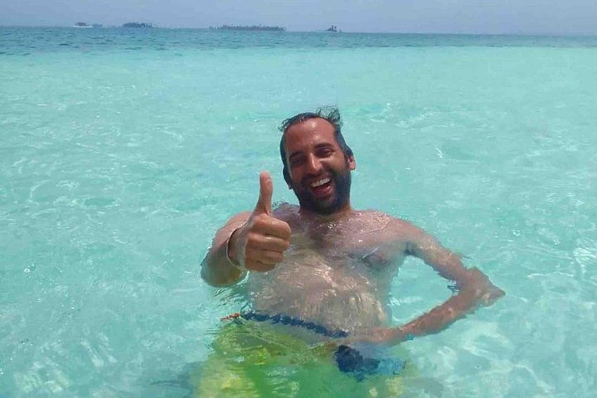 A person giving a thumbs-up gesture in clear turquoise water. 5