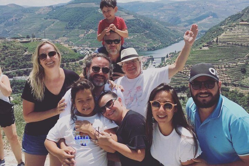 A group of people posing on a hillside with a river and terraced fields in the background. 2
