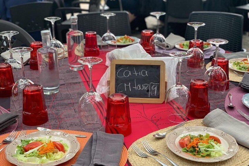 A dining table set with red glassware, plates with salads, and a chalkboard sign reading "Café M Hourz". 4
