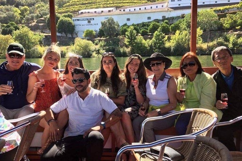 A group of people sitting on a boat with a scenic view of a building and greenery in the background. 5