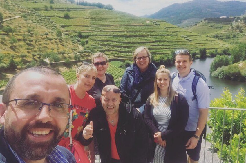 Un grupo de personas en una terraza con vistas a viñedos en terrazas y un río. 2