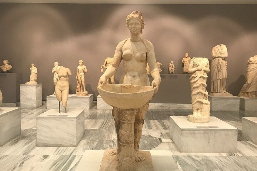 A museum display with classical sculptures, including a central figure holding a bowl. 4