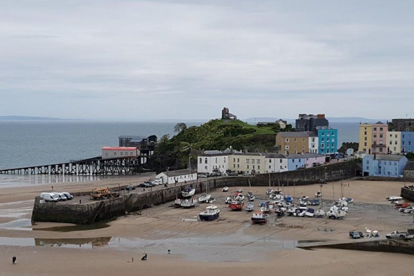 Une ville côtière aux bâtiments aux couleurs vives, avec une jetée et des bateaux sur la plage. 4