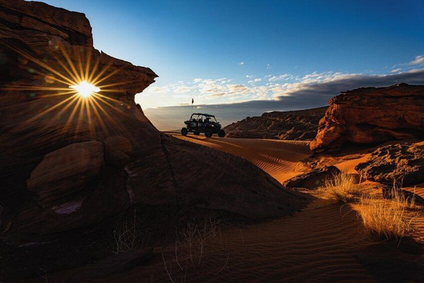 Un jeep en un sendero desértico con una formación rocosa y cielo despejado. 1