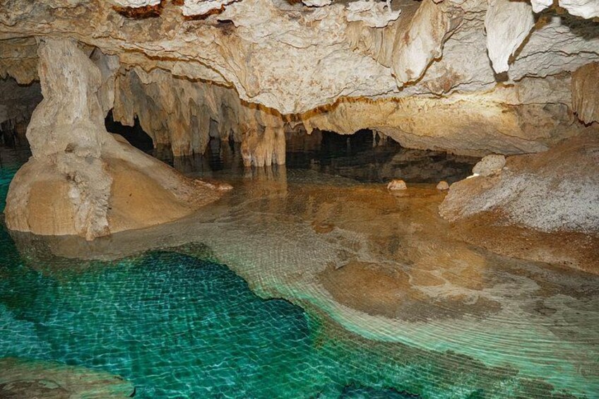 En grotta med stalaktiter och en pool med klart vatten. 2