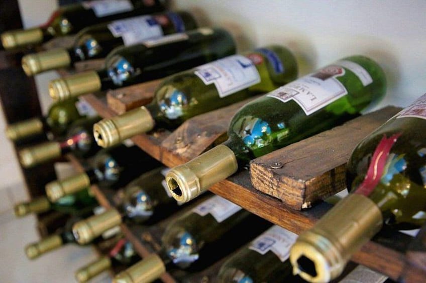 A collection of wine bottles on wooden shelves. 2