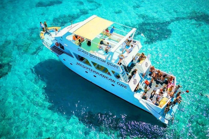 Un'ampia imbarcazione chiamata 'Glass Bottom Reef' con persone a bordo, che galleggia su acque turchesi cristalline. 1
