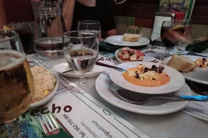 Une table à manger avec des assiettes remplies de nourriture, des verres d’eau et de vin, et un menu. 2