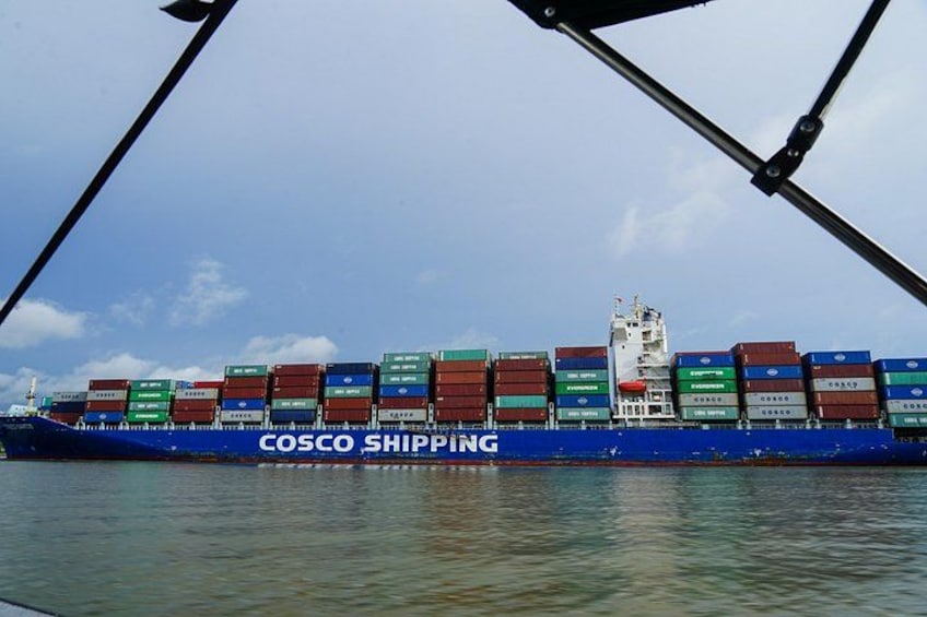 A large blue container ship with multiple stacked containers, labeled 'COSCO SHIPPING,' sailing on the water. 2