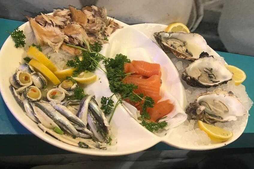 A seafood platter with various types of fish, including salmon and oysters, garnished with lemon and parsley. 5