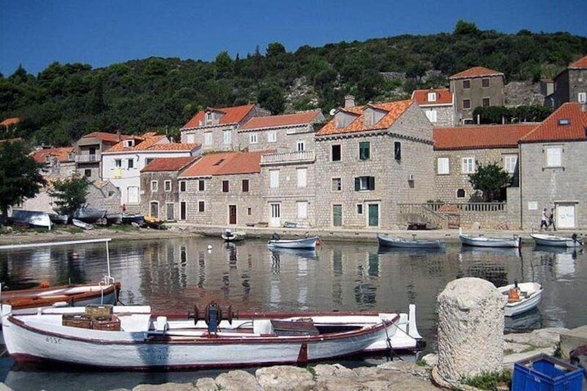 A harbor with boats, stone buildings, and a hillside in the background. 2