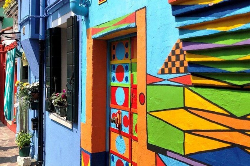 Un bâtiment aux couleurs vives, orné de motifs géométriques, et doté d’une fenêtre avec des volets noirs. 2