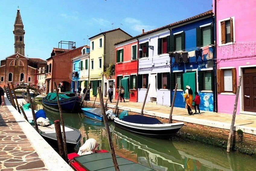 Un canal con barcos, edificios coloridos y una torre de iglesia. 3