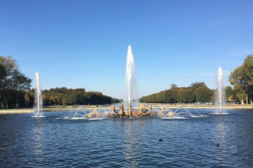 Una fuente con chorros de agua en un parque con árboles y cielo despejado. 5