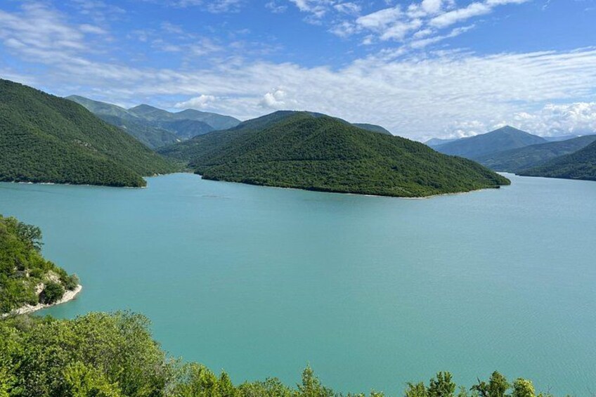Un lago rodeado de montañas, cielos despejados y abundante vegetación. 4