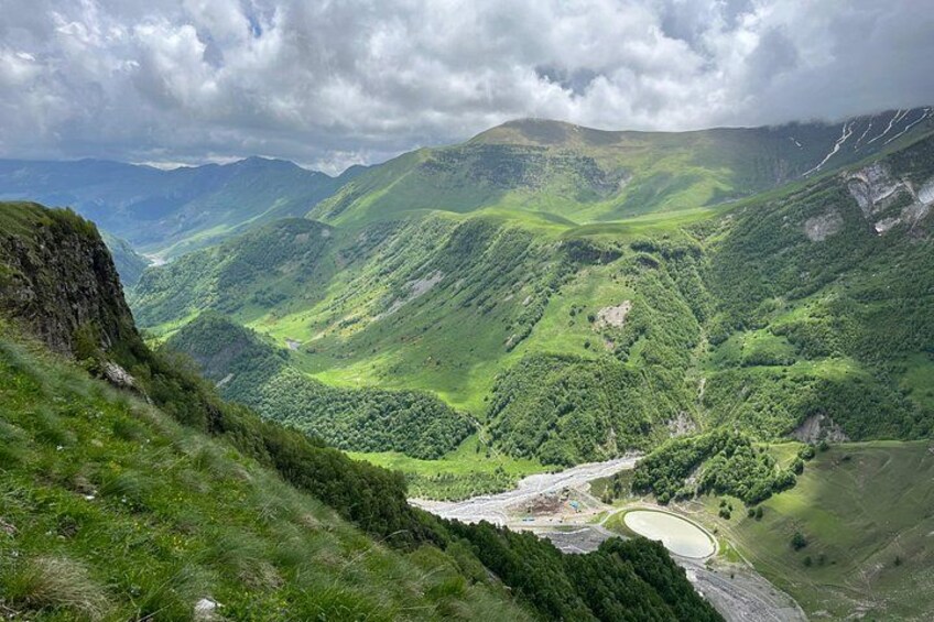 Un paisaje montañoso con un río serpenteante, bosques densos y un pequeño lago. 2