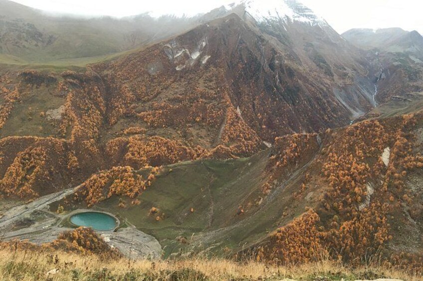 Un paisaje montañoso con un lago y árboles de colores otoñales. 5