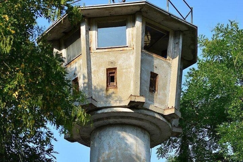 Una torre de observación de concreto con barandilla metálica, rodeada de árboles. 2