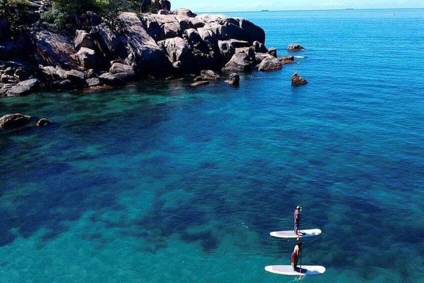 Una persona fa paddleboarding su acqua cristallina vicino a coste rocciose. 2