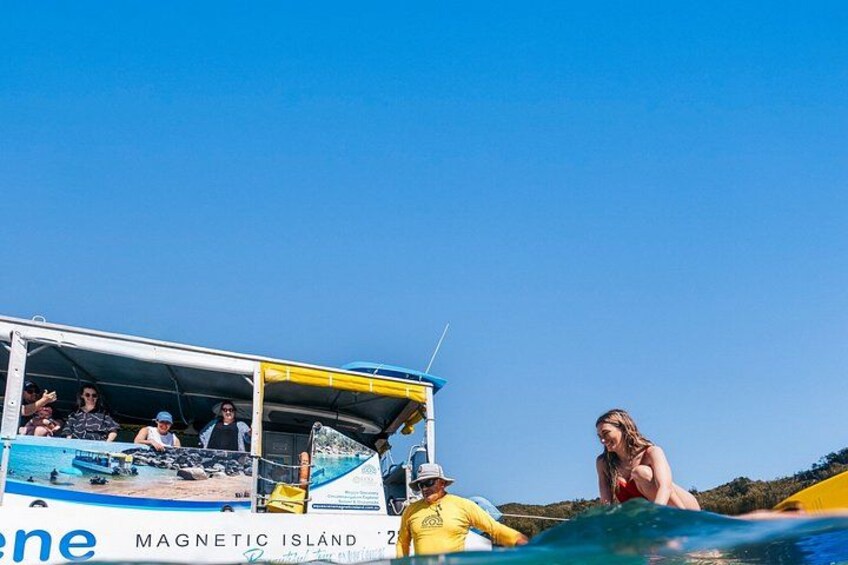 A boat with people on board, a clear blue sky, and a beach in the background. 3