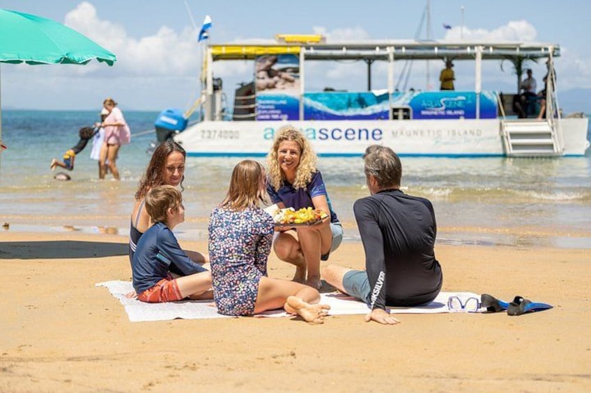Een groep mensen zit op het strand, met een boot op de achtergrond. 5