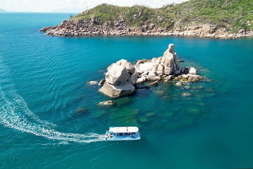 A boat navigating near a rocky island surrounded by clear blue water. 2