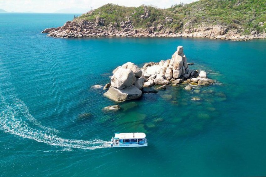 Una barca che solca acque cristalline vicino a un'isola rocciosa. 4