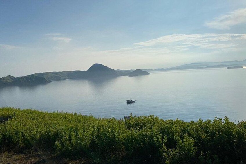 Un lac paisible avec une petite barque, une végétation verdoyante au premier plan et des collines lointaines. 3
