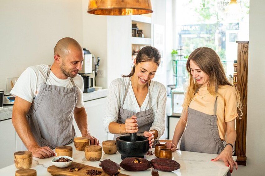 Three people in a kitchen with wooden bowls and a black pot on the counter. 3