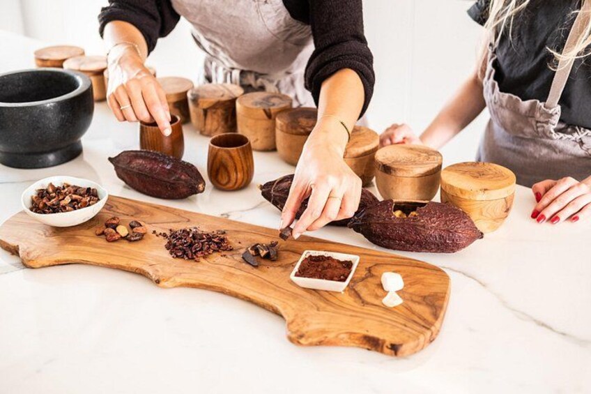 A person preparing food with various ingredients and wooden containers on a marble countertop. 2