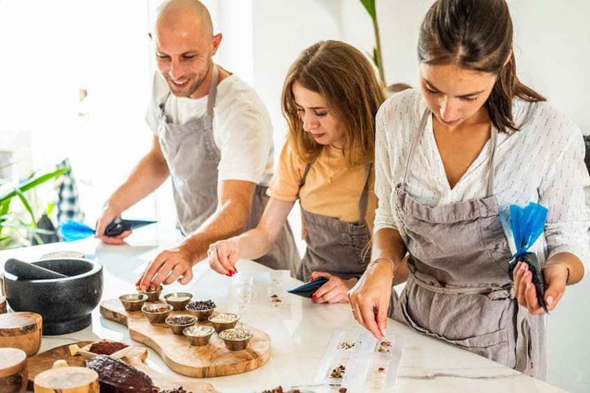 Tres personas preparando comida con diversos ingredientes y utensilios sobre una encimera de cocina. 2